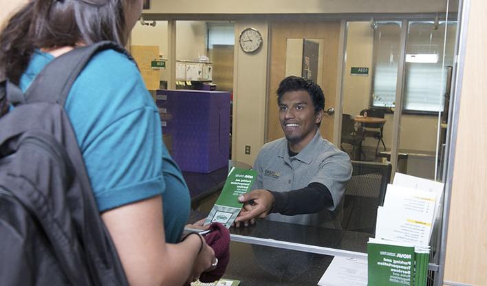 A student receiving a brochure from a staff member